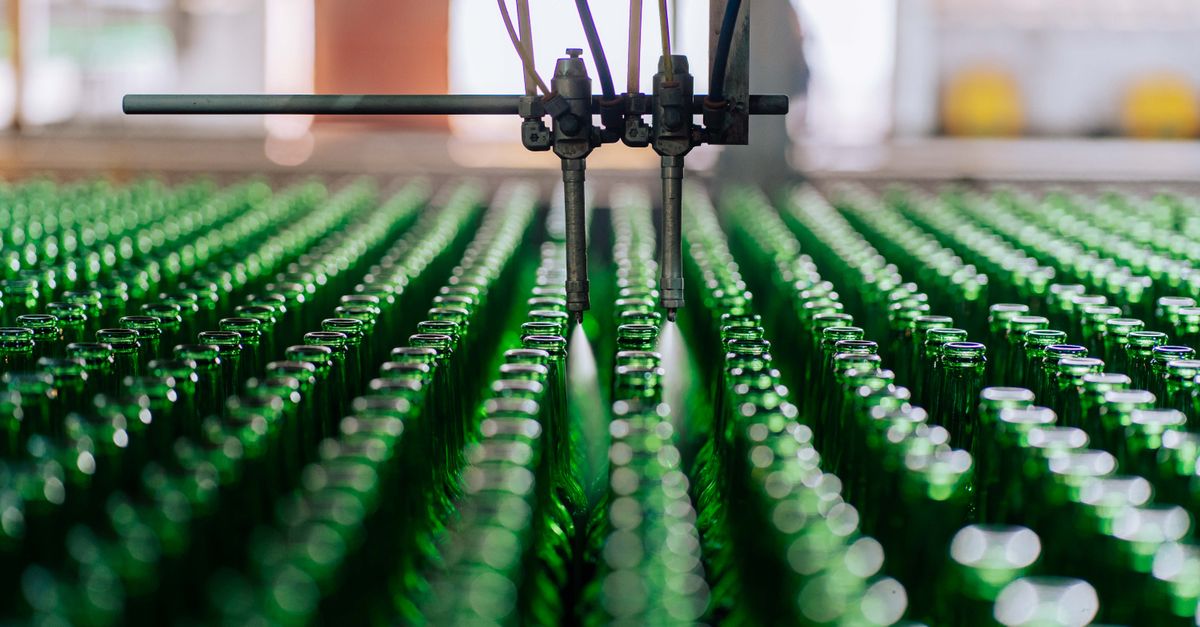 Glass bottles on an automated line in a factory, showcasing industrial glass making.