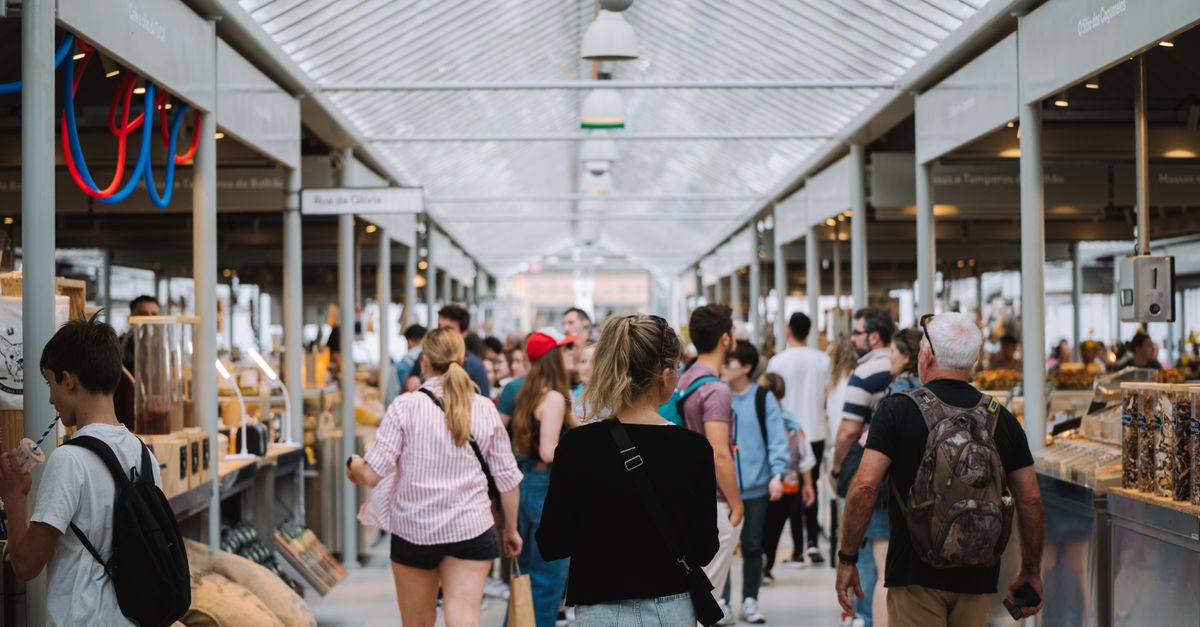 People exploring a vibrant indoor market with modern architecture and diverse stalls.