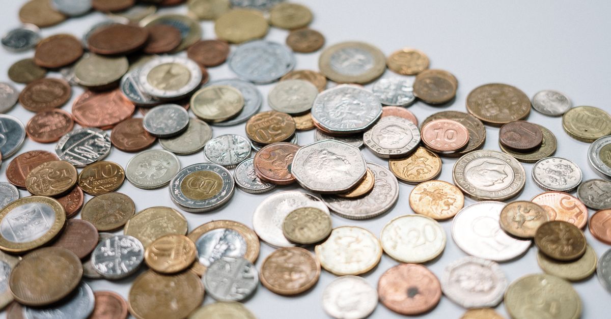 A diverse collection of international coins spread across a white surface, showcasing various currencies and designs.