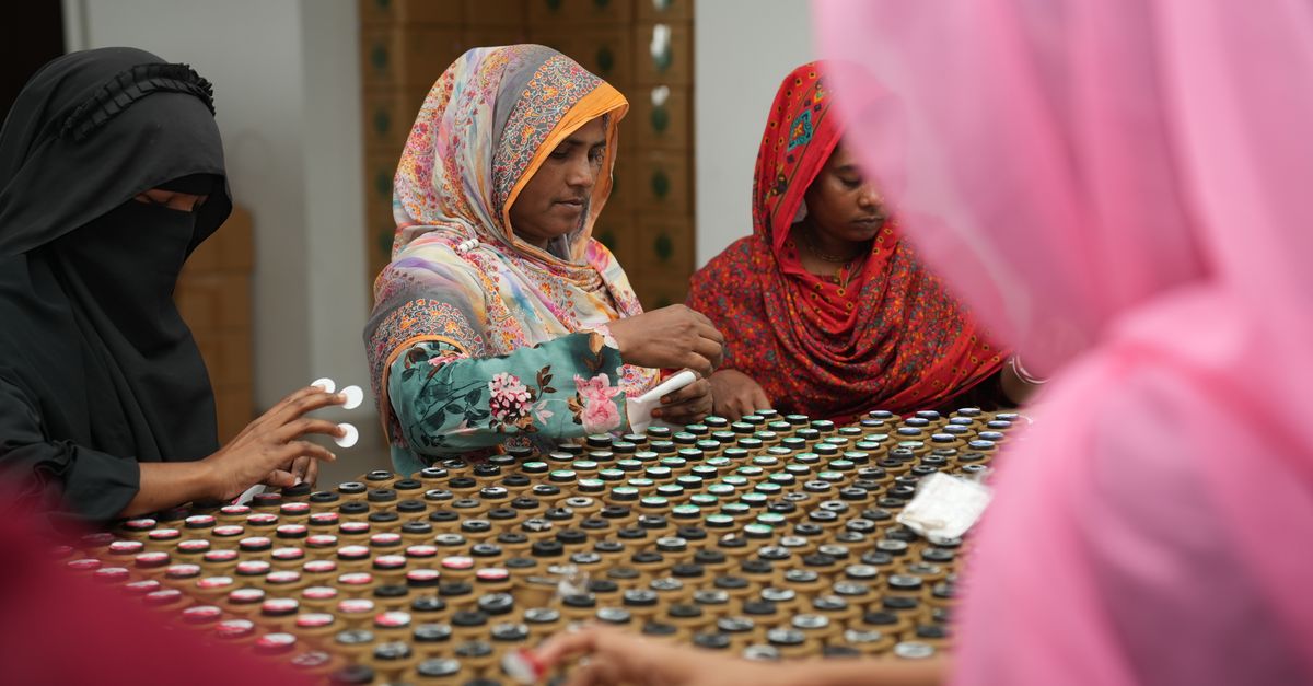 Portrait of women in traditional attire sorting products in a factory.