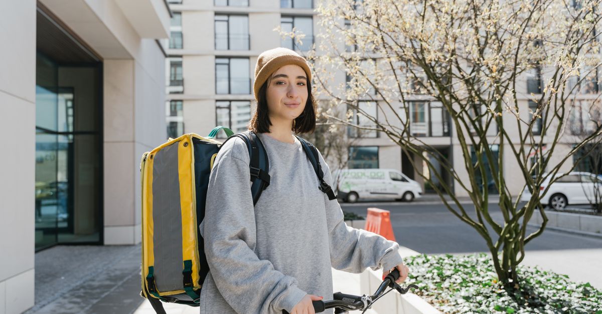 Young woman cyclist with a delivery backpack on a city street ready for food delivery.