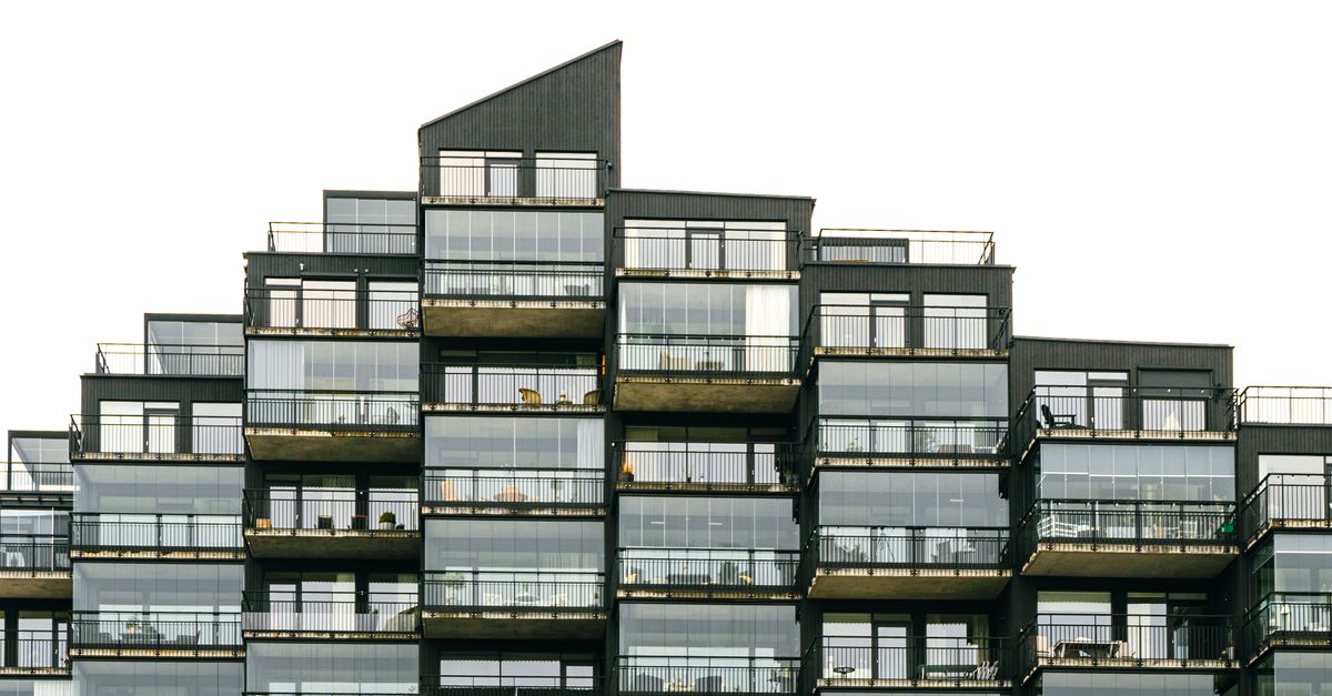 Contemporary apartment building with geometric facade and glass balconies, showcasing modern architecture.