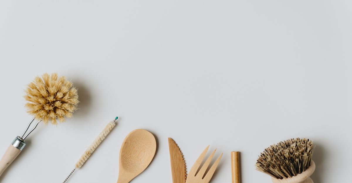 Sustainable wooden kitchen utensils and brushes on a white background, promoting eco-friendly living.