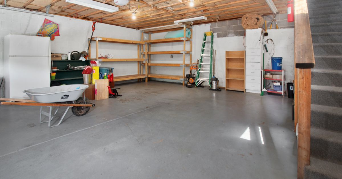 Spacious garage interior with storage shelves, tools, and a wheelbarrow, ideal for home organization.