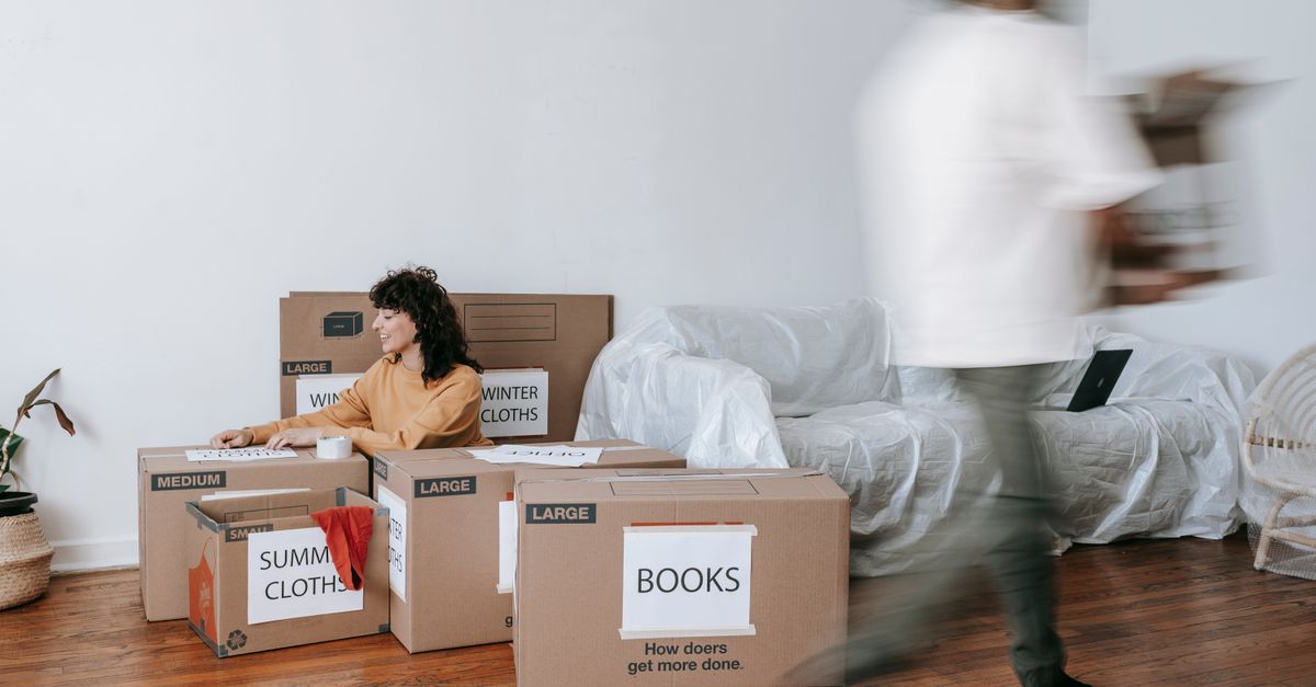 A couple packing labeled boxes in a minimalist living room, preparing for moving day.