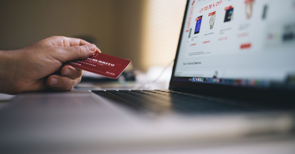 Person holding a credit card while shopping online on a laptop, indicating ecommerce transactions.