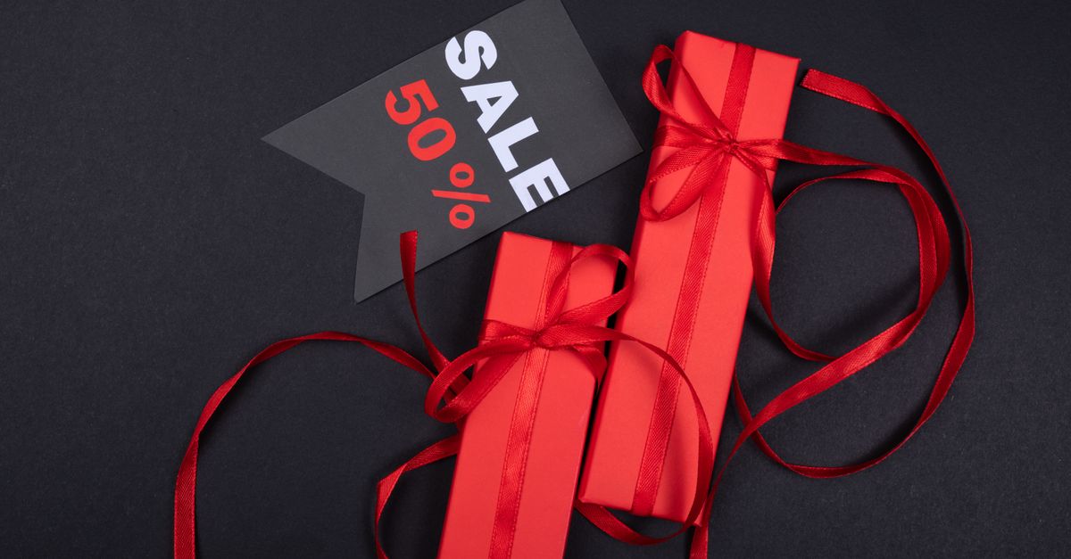 Red gift boxes with ribbons and 50% sale tag against black background.