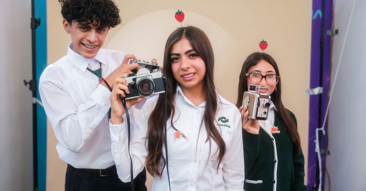 Three students pose with vintage cameras, showcasing school pride in Irapuato, Mexico.