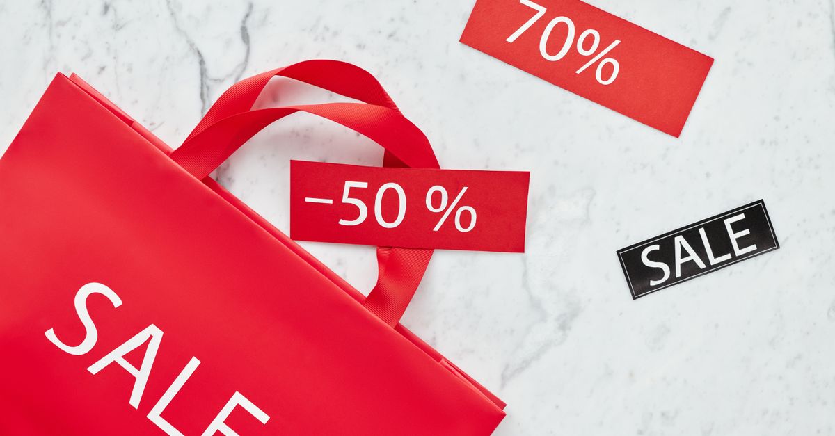 Red sale bag with 50% and 70% discount tags on marble background, perfect for retail promotions.