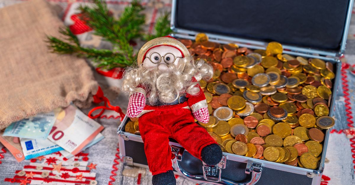 Small Santa figurine with euro coins and Christmas decorations in a festive setting.