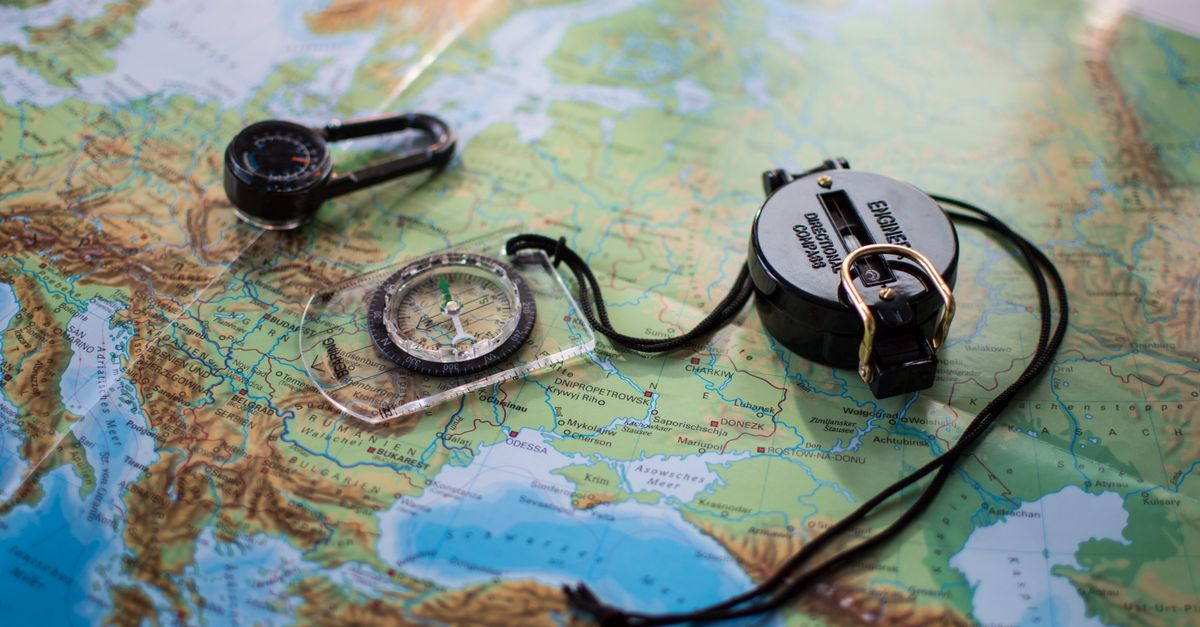 Flat lay of a European map with two compasses, symbolizing travel and exploration.