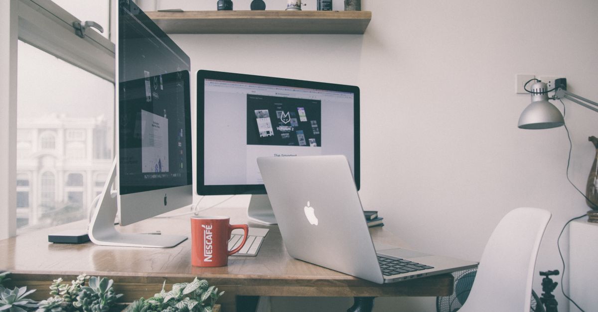 Sleek home office setup with dual monitors, a laptop, and minimalist decor.