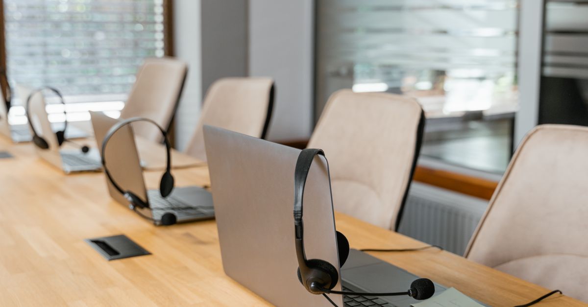 Row of laptops with headsets in a modern office environment ready for communication.