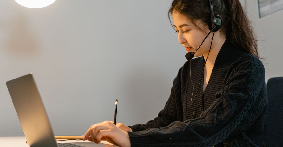 Focused call center agent working on a laptop with headphones. Customer service professional in an office setting.