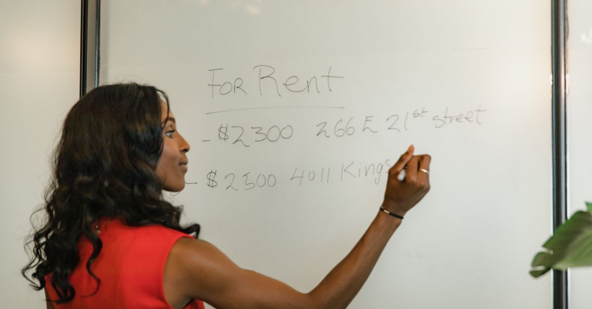 Professional woman writing real estate prices on a whiteboard for rental properties.