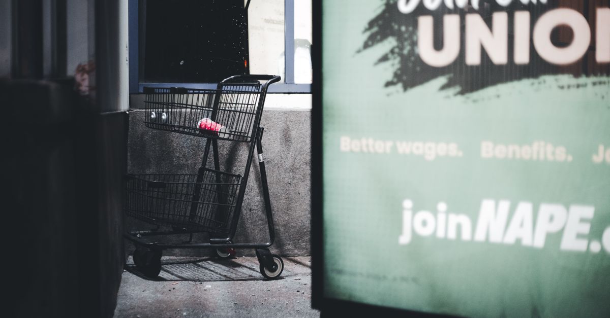 Dramatic urban scene featuring an empty shopping cart and a union sign at night.