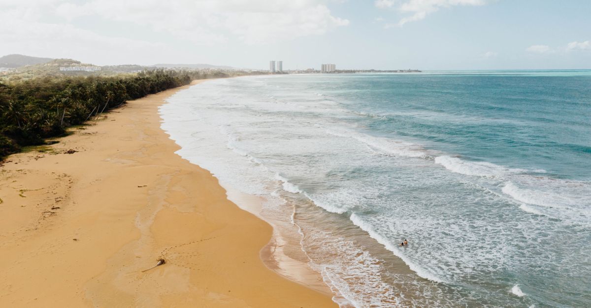 Golden sand beach in Puerto Rico with gentle waves, ideal for a tropical summer vacation.