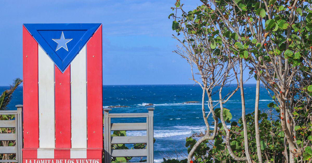 Colorful Puerto Rican flag mural at La Lomita de los Vientos with ocean view.