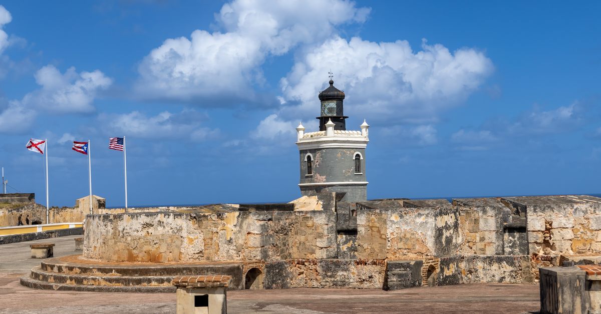Lighthouse at Castillo San Felipe del Morro in San Juan, Puerto Rico, under a clear blue sky.