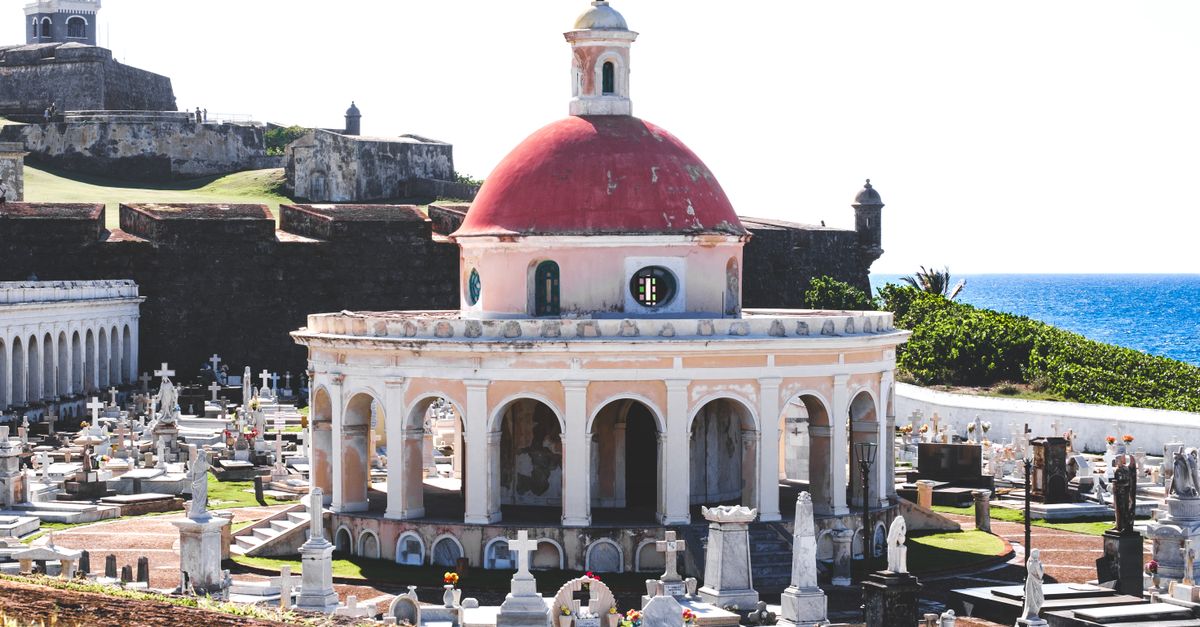 A picturesque view of the historic cemetery in Old San Juan, Puerto Rico, featuring ornate tombstones and ocean backdrop.