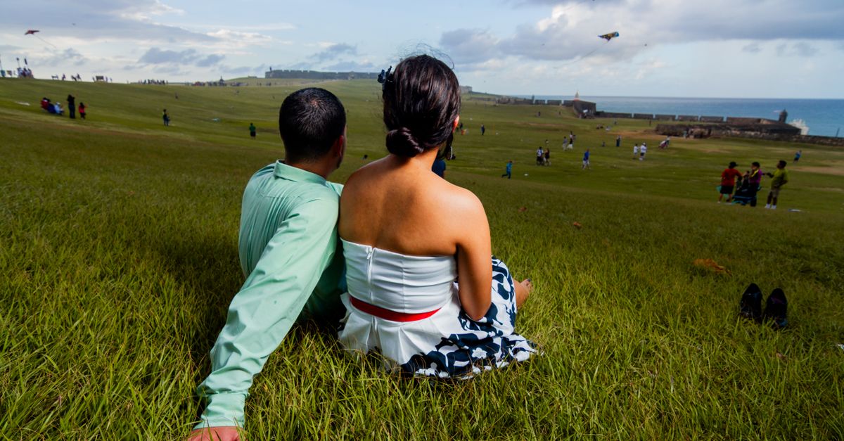 A couple enjoys a scenic view at San Juan's historic fortress park, surrounded by flying kites.