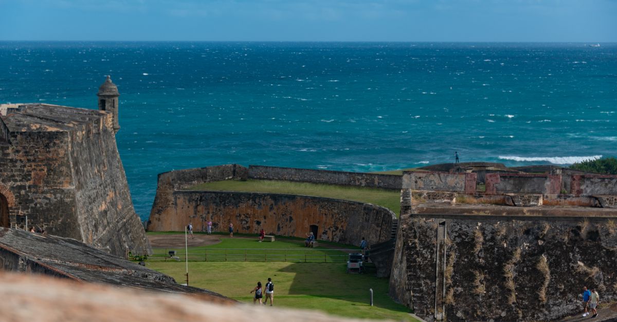 Explore a historic seaside fortress with tourists in Puerto Rico, offering scenic ocean views.