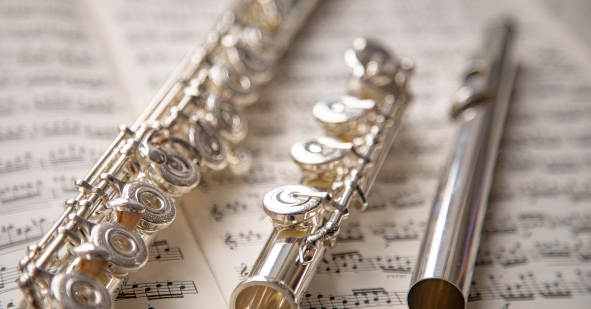 Elegant silver flutes resting on sheet music, showcasing classic musical beauty.