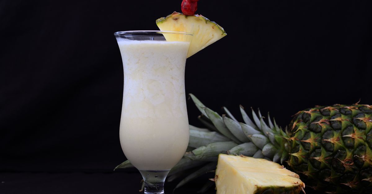 A refreshing pina colada garnished with fresh pineapple slices, ideal for tropical settings.