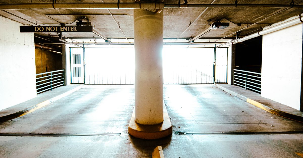 A brightly lit empty parking garage with a central pillar and 'Do Not Enter' sign.