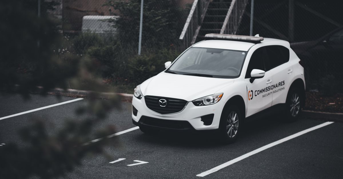 A white SUV with security branding parked in a numbered outdoor spot.