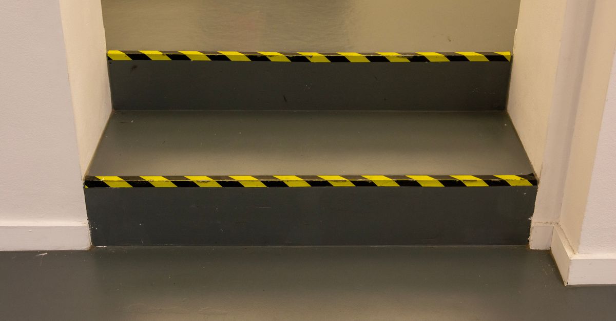 Green steps with black and yellow caution tape in an interior hallway for safety.