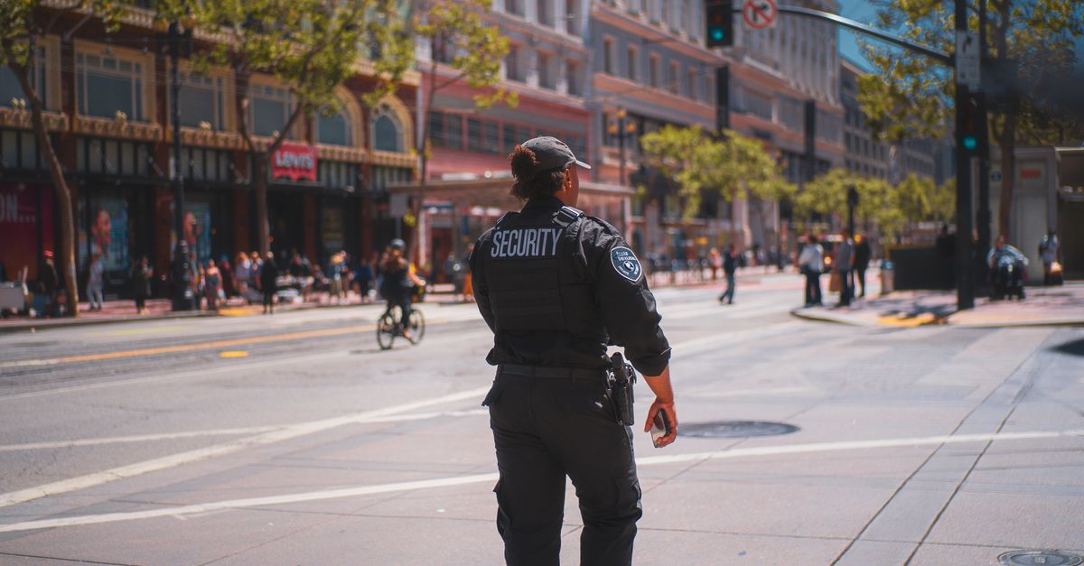 A security officer patrols a bustling street in San Francisco, capturing daily urban life.