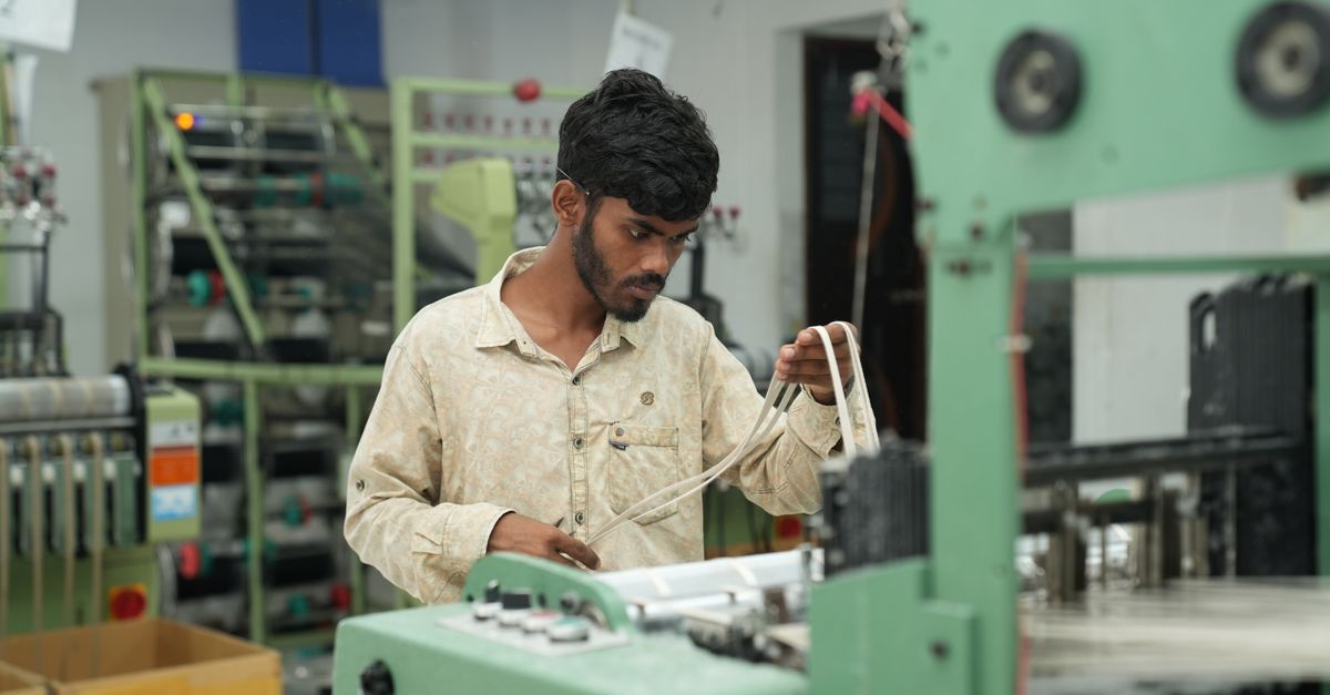 A man intently operates machinery in a modern factory setting, overseeing production lines.