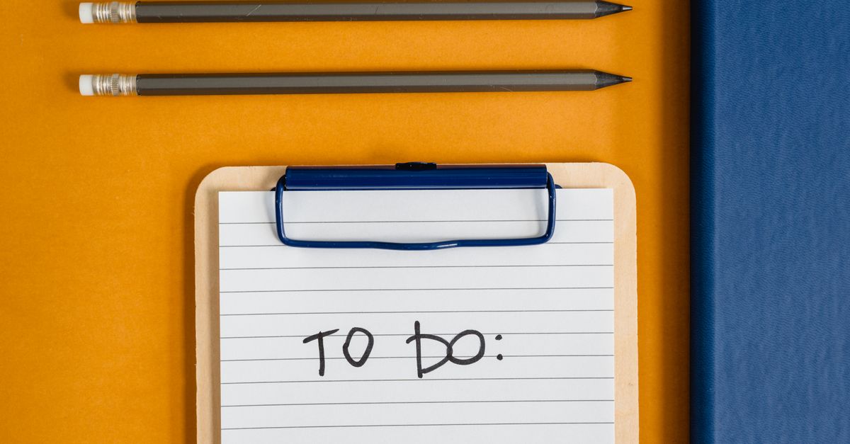 Flat lay of office supplies including a clipboard with a To-Do list, pencils, and a notebook on a yellow surface.