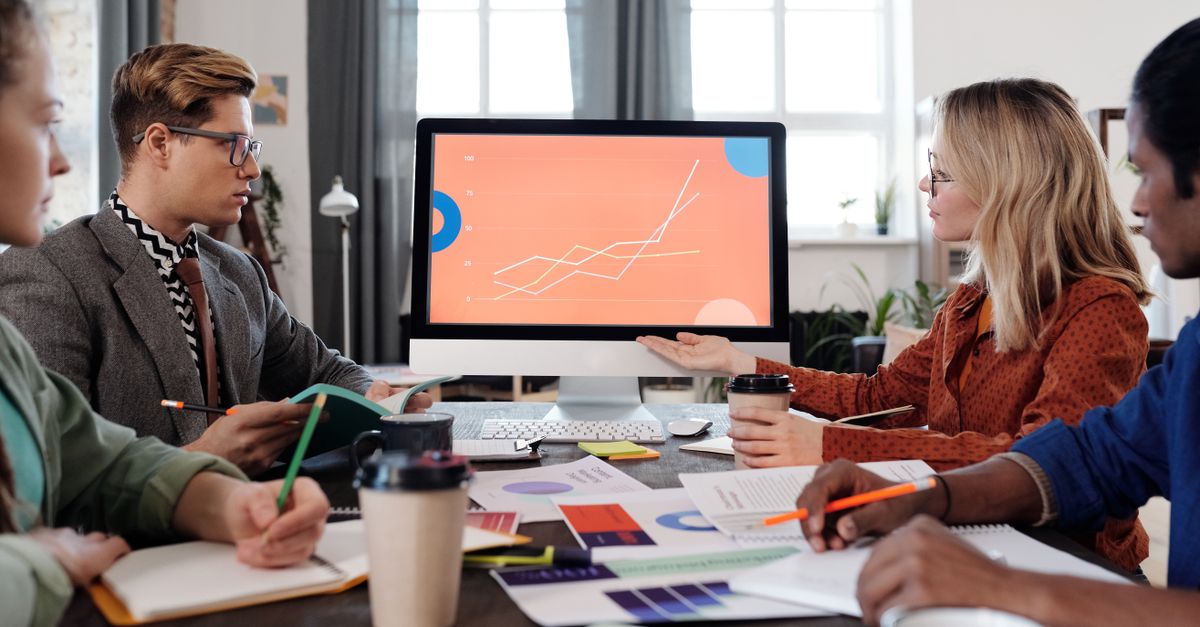 A diverse team discusses data visualization on a computer screen in an office setting.