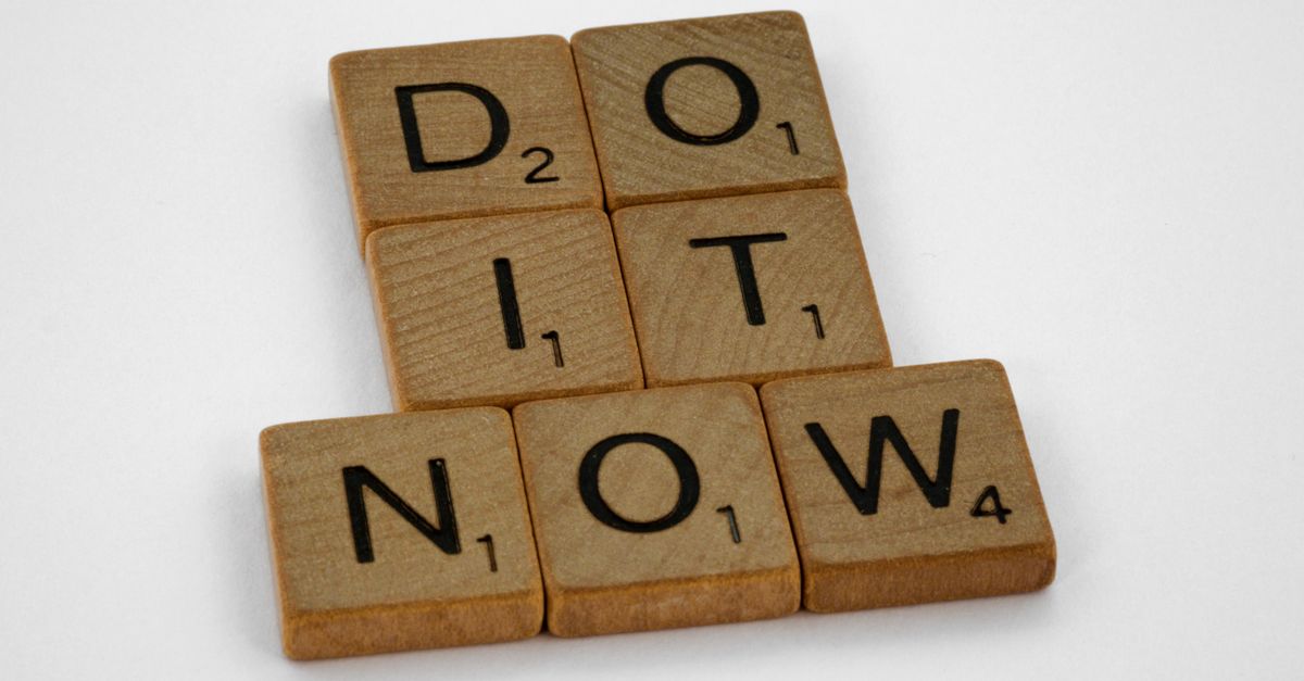 Wooden scrabble tiles forming 'DO IT NOW' on a minimal white backdrop. Inspiring concept.
