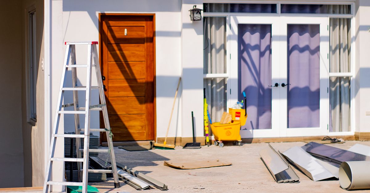 Front entrance of a house under renovation with tools and materials scattered around.