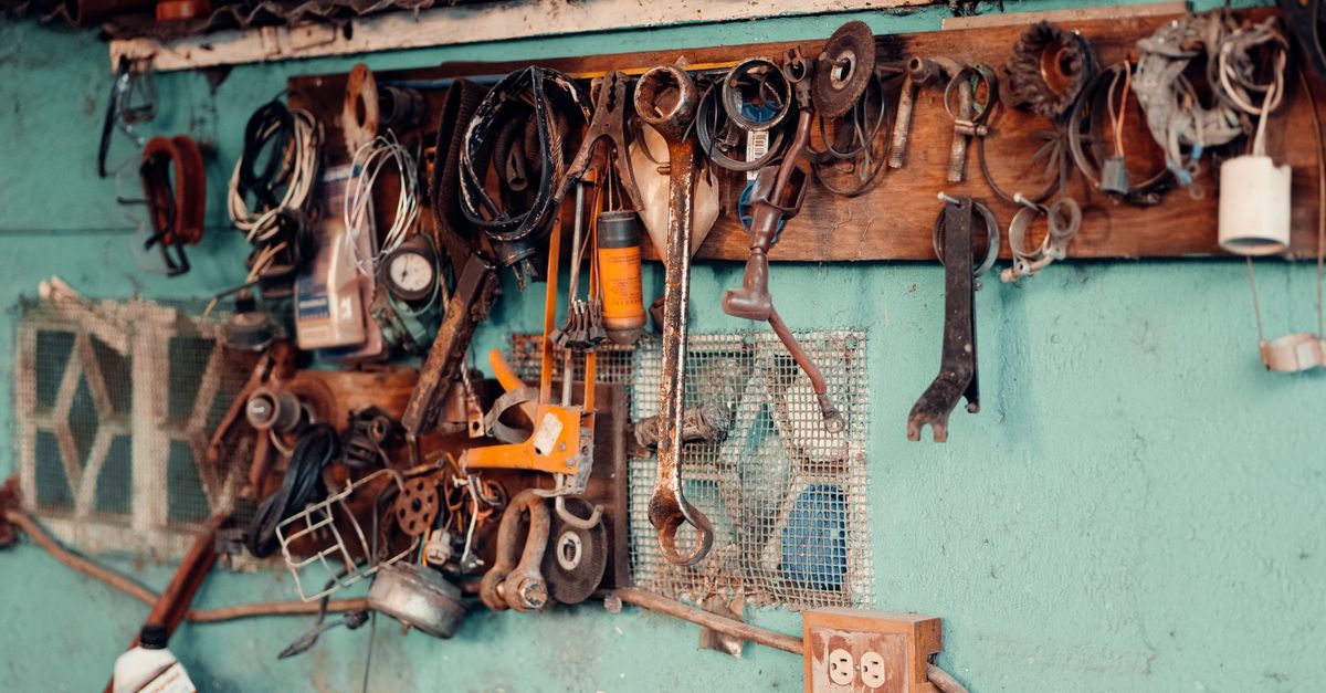 A collection of vintage tools hangs on a rustic workshop wall, creating a nostalgic and creative atmosphere.