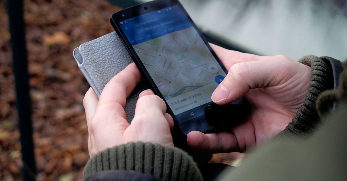 Close-up of hands using a map app on a smartphone outdoors, showcasing GPS navigation.