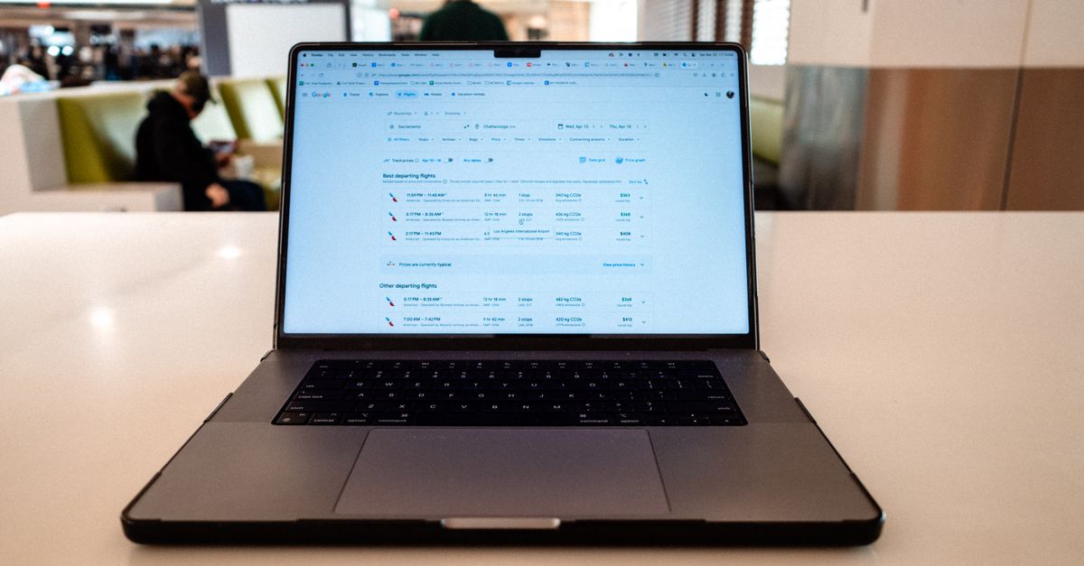 A modern laptop displaying flight schedules on a white table in an airport lounge.