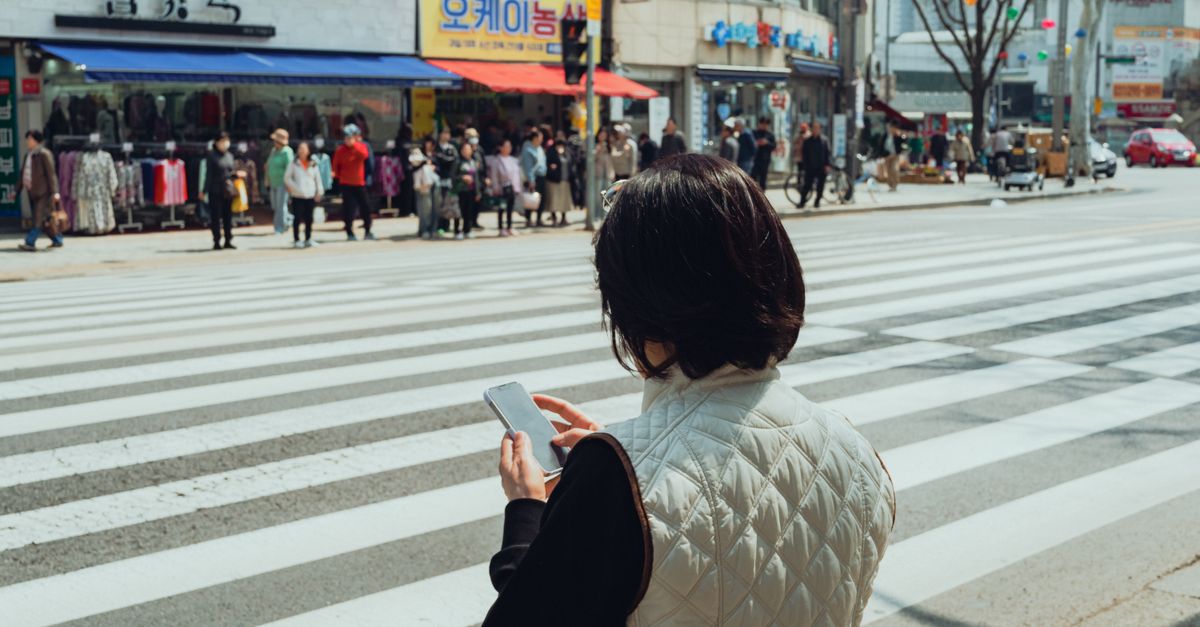 A woman checks her phone while crossing a busy street in Suwon, South Korea.