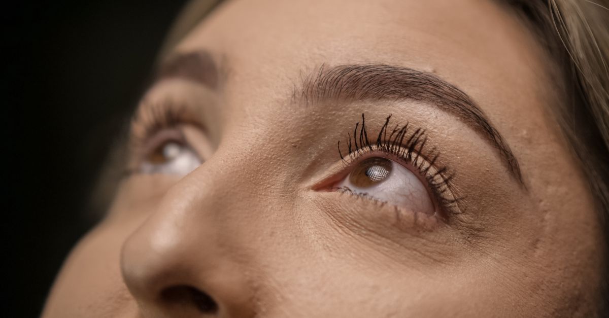 Detailed close-up of female eyes looking upwards with long eyelashes and soft focus.