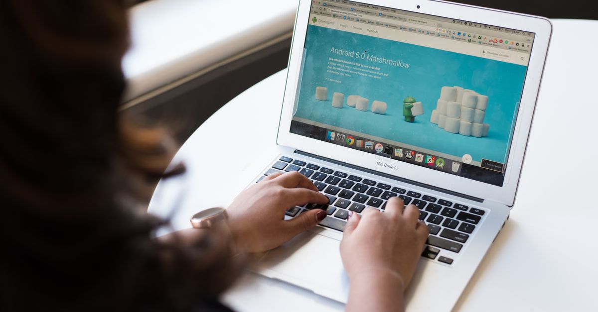 Businesswoman working on laptop with Android 6.0 Marshmallow webpage open.