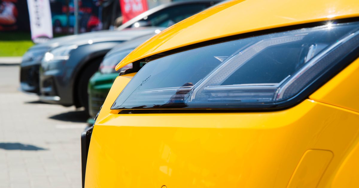 Vibrant yellow car headlight close-up in a sunny outdoor parking lot.