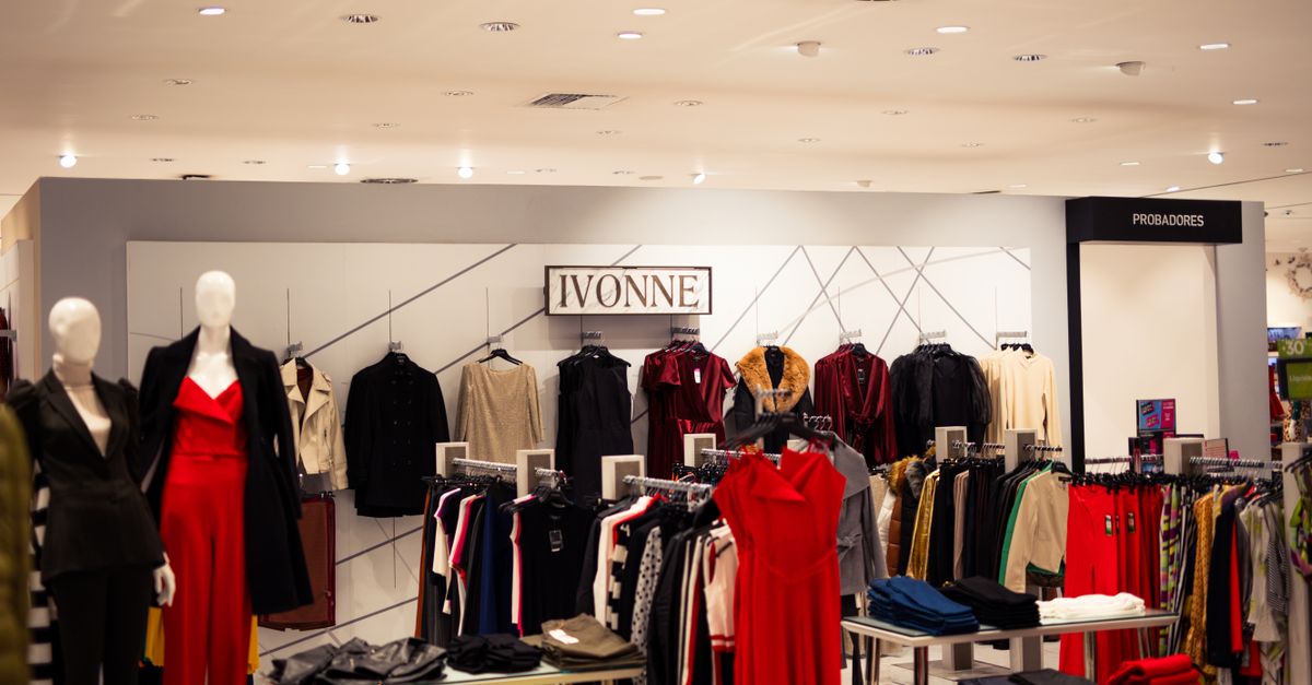 A stylish fashion boutique displaying elegant clothing on mannequins under bright lights.