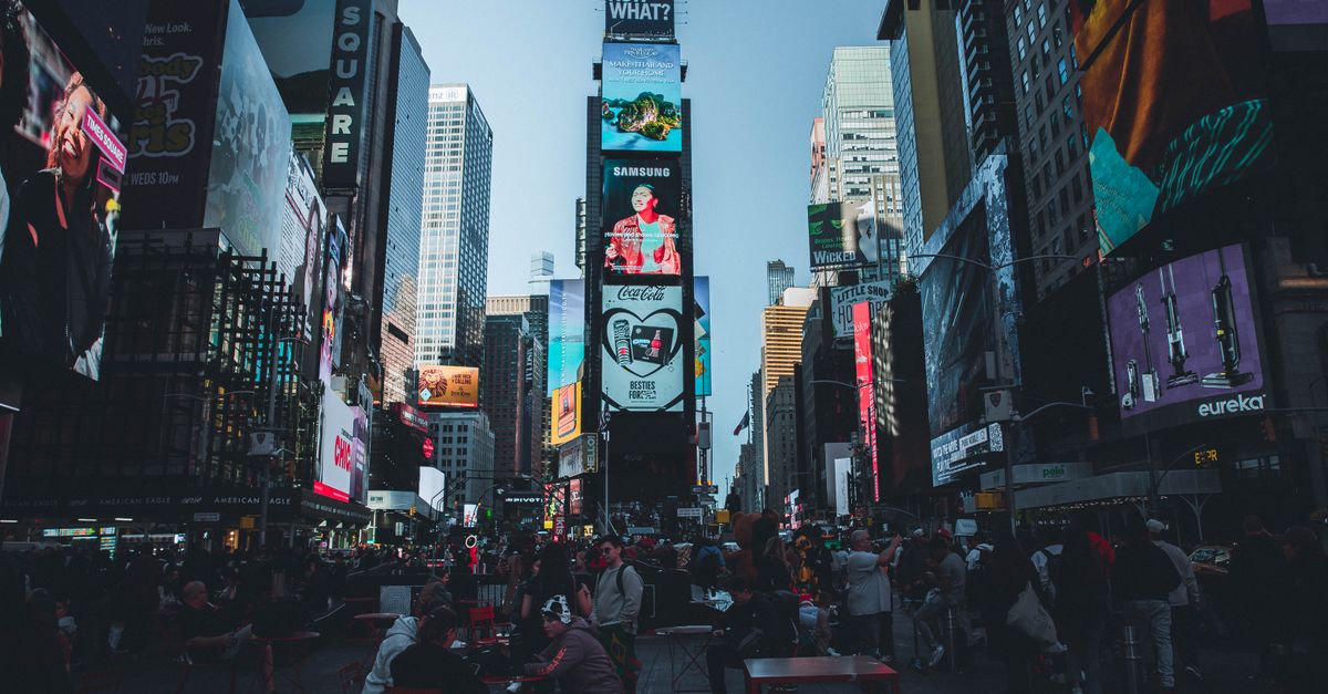Vibrant Times Square in New York City filled with people and bright billboards during the day.