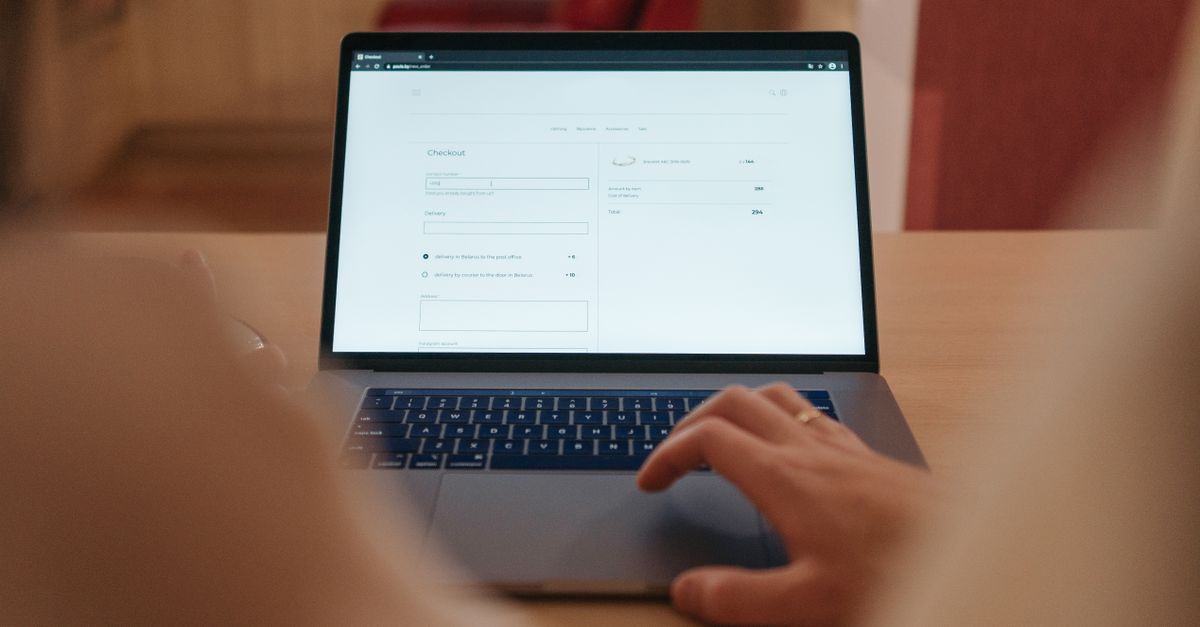 Close-up of a person navigating online checkout on a laptop screen in a cozy indoor setting.