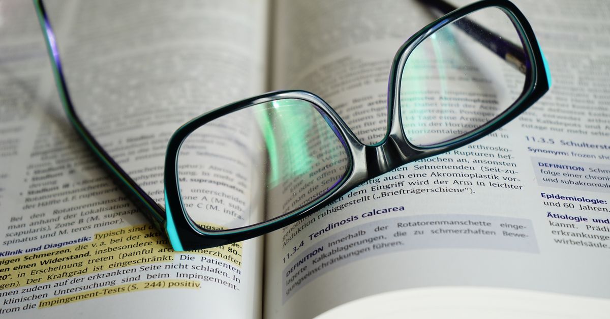Reading glasses resting on an open book, symbolizing knowledge and learning.