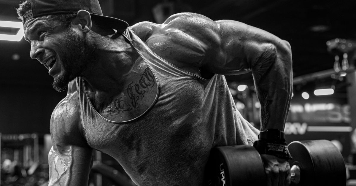 Muscular man lifting dumbbells at the gym in a black and white shot.