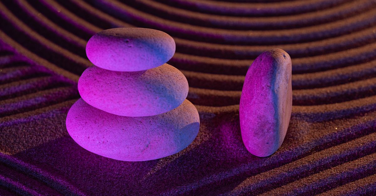 Serene zen garden with stacked stones in a purple light surrounded by sand patterns symbolizing balance and tranquility.